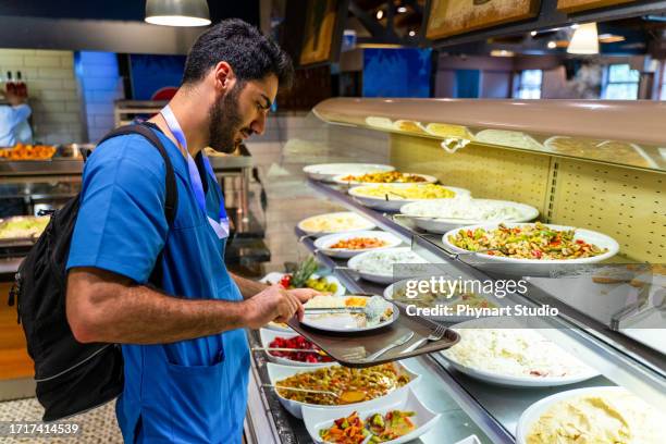 man in medical scrubs eating at a buffet style cafeteria - merenda escolar imagens e fotografias de stock