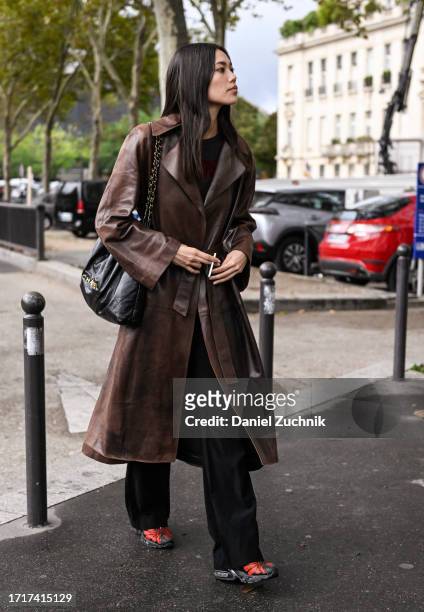 Model Jade Nguyen is seen wearing a brown leather trench coat and black and gold chain bag outside the Chanel show during the Womenswear...