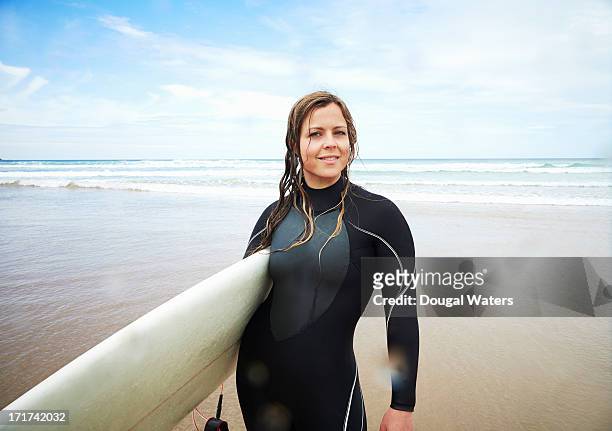 portrait of female surfer at beach. - beach hold surfboard stock-fotos und bilder