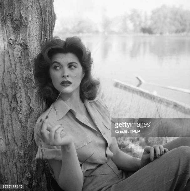 Portrait of American Actress Tina Louise, leaning against a tree, as she poses outdoors, 1958.