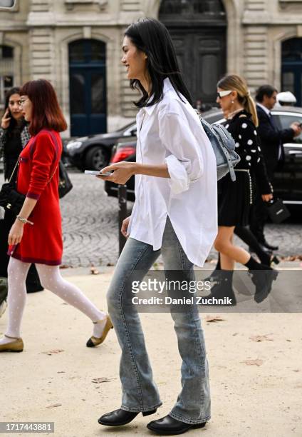 Model Qun Ye is seen wearing a white button shirt, skinny jeans and black boots outside the Chanel show during the Womenswear Spring/Summer 2024 as...