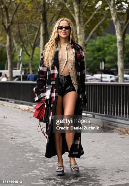 Guest is seen wearing a plaid coat, tan cardigan, black Miu Miu shorts and red bag with black sunglasses outside the Chanel show during the...