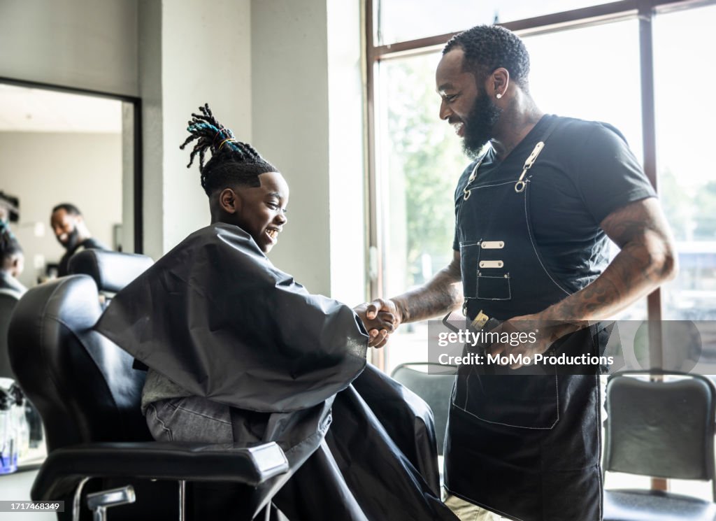 Barber cutting young boys hair in barbershop