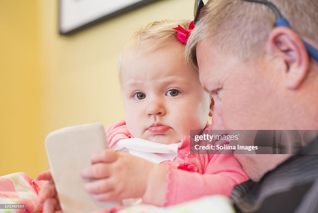Baby girl holding smartphone with dad closed toher