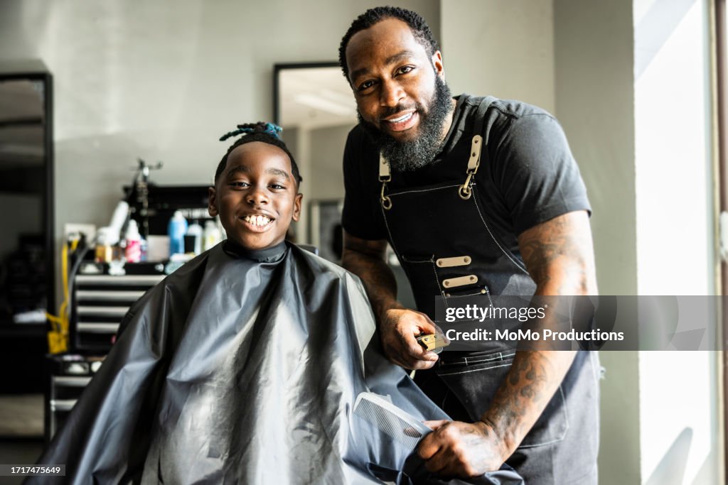 Portrait of barber and young customer in barber shop