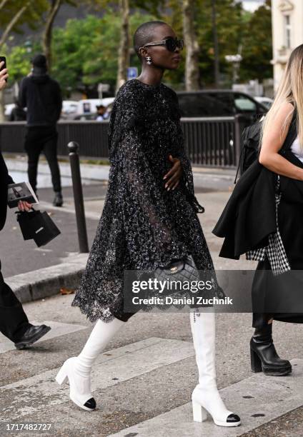 Model is seen wearing a Chanel dress, white boots and Chanel bag with black sunglasses outside the Chanel show during the Womenswear Spring/Summer...