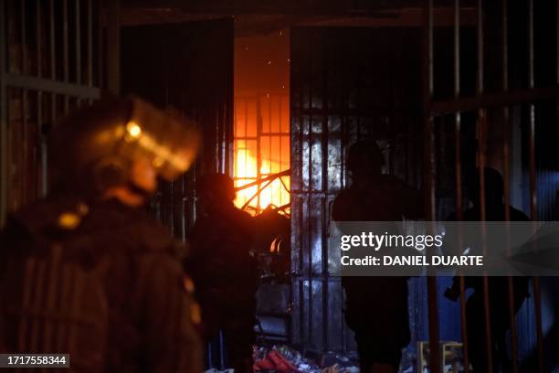 Security forces stand near a fire burning inside the Tacumbu prison after hundreds of inmates took the facility, in Asuncion, on October 10, 2023....