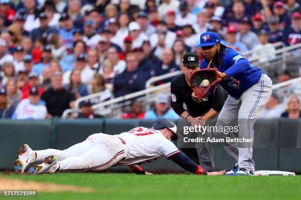 Ryan Jeffers of the Minnesota Twins slides safe at first base against Vladimir Guerrero Jr. #27 of the Toronto Blue Jays during the seventh inning in...