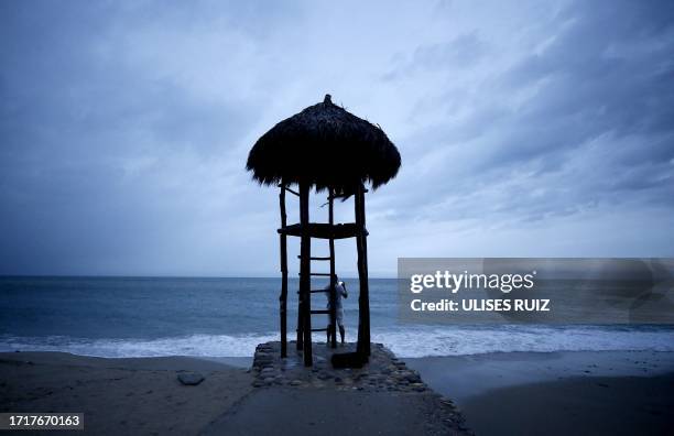 Man takes pictures under a beach lifeguard watch hut in Puerto Vallarta, Jalisco State, Mexico, on October 10 as Hurricane Lidia came ashore near...