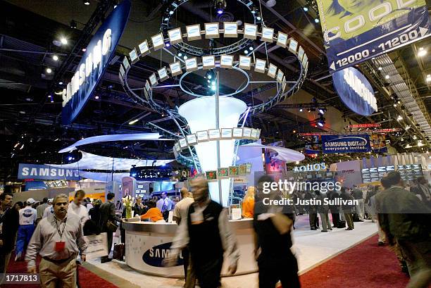 People walk past the Samsung booth at the 2003 International Consumer Electronics Show January 9, 2003 in Las Vegas. The show is expected to draw...