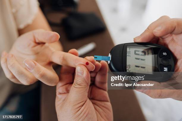 enfermera midiendo la glucosa del paciente en casa - diabetes fotografías e imágenes de stock