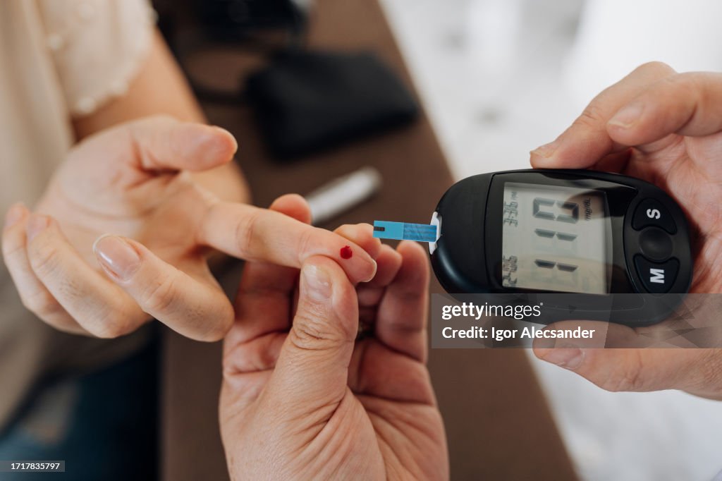 Nurse measuring patient's glucose at home