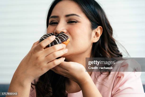 donna felice sovrappeso con una ciambella - fat people eating donuts foto e immagini stock