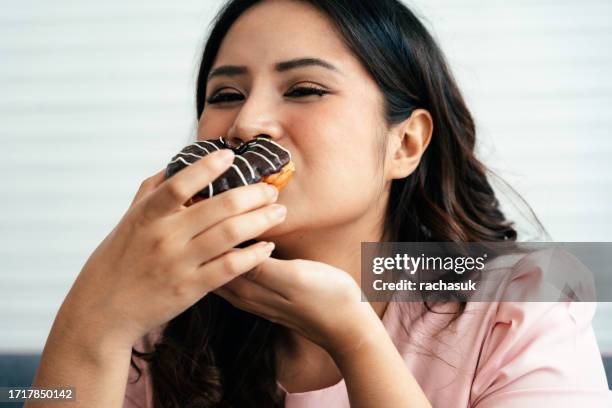 overweight happy woman with a donut - sweet tooth adult stock pictures, royalty-free photos & images