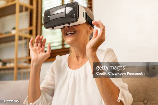 happy senior woman using vr headset to play online video game and connect to social media - real time stock pictures, royalty-free photos & images