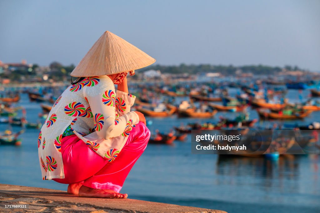 Vietnamese woman looking at fishermen's boats, Vietnam