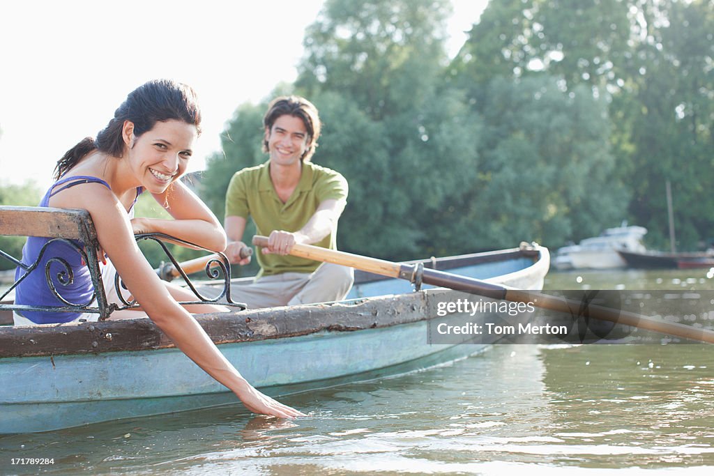 Man rowing girlfriend in rowboat on lake