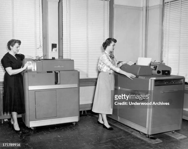 Women using two different IBM punch card machines, Cleveland, Ohio, circa 1954. On the left is a Summary Punch Machine, and on the right is the type...