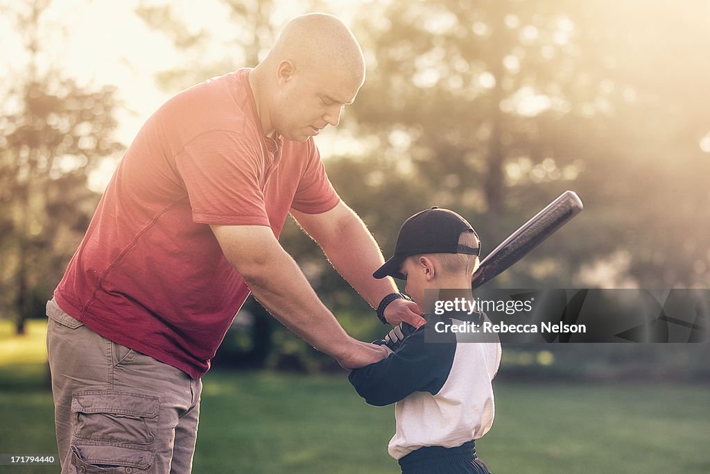 Father teaching son how to hold a baseball bat