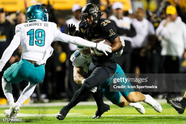 Mason Shelton and Abraham Temoney III of the Coastal Carolina Chanticleers attempt to tackle Maquel Haywood of the Appalachian State Mountaineers as...
