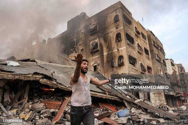 Man reacts outside a burning collapsed building following Israeli bombardment in Gaza City on October 11, 2023. At least 30 people have been killed...