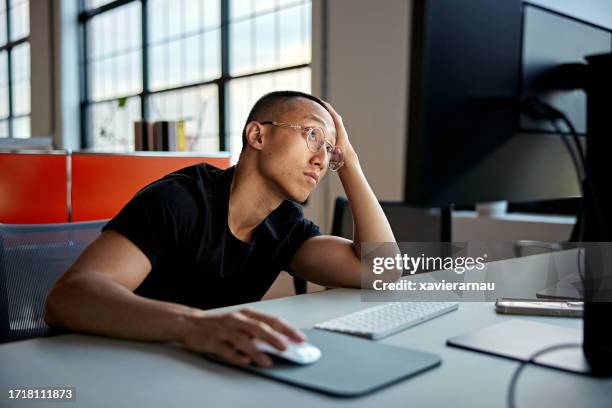 デスクトップpcで日常業務を行うアジアのサラリーマン - つまらない仕事 ストックフォトと画像