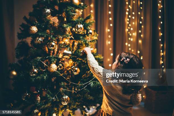 little girl decorating christmas tree. - intérieur deco prendre la pose joie photos et images de collection