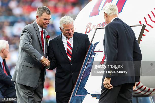 Chipper Jones of the Atlanta Braves shakes hands with general manager Frank Wren during his number retirement ceremony before the game against the...