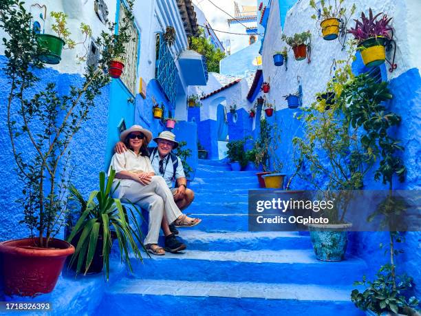 mature couple posing on stairway in chefchaouen, morocco - morocco stock pictures, royalty-free photos & images