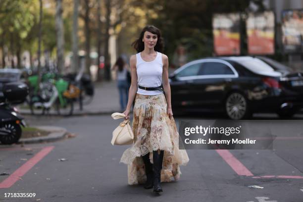 Mary Leest is seen outside Zimmermann show wearing white tank top, black belt above with golden hardware, beige flower lace skirt, vanilla colored...