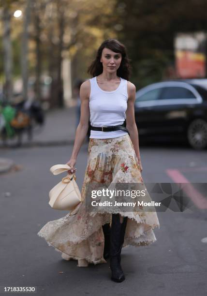 Mary Leest is seen outside Zimmermann show wearing white tank top, black belt above with golden hardware, beige flower lace skirt, vanilla colored...