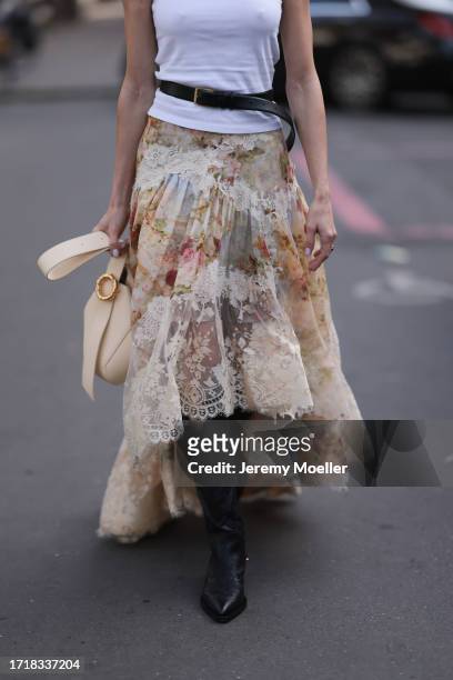 Mary Leest is seen outside Zimmermann show wearing white tank top, black belt above with golden hardware, beige flower lace skirt, vanilla colored...