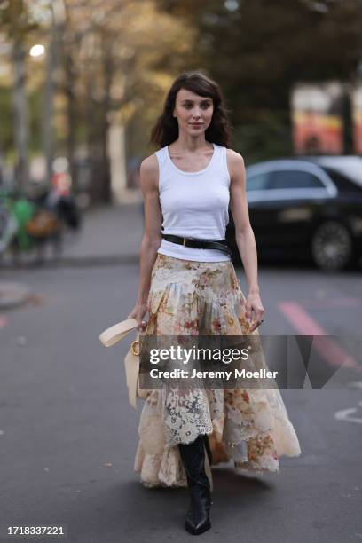 Mary Leest is seen outside Zimmermann show wearing white tank top, black belt above with golden hardware, beige flower lace skirt, vanilla colored...