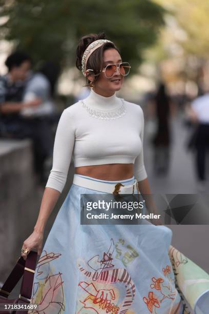 Ashley Park is seen outside Zimmermann show wearing golden sunnies with orange shades, crystal beige headband, white turtle neck cropped top with...