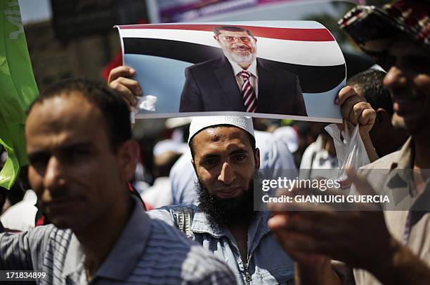 An Egyptian protester holds a picture of President Mohamed Morsi as Islamists and Muslim Brotherhood supporters gather at the Rabaa al-Adawiya mosque...