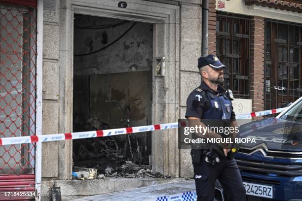 Police officer stands guard next to a building where four minors were killed in a fire in Vigo on October 11, 2023. Four minors have died in a fire...