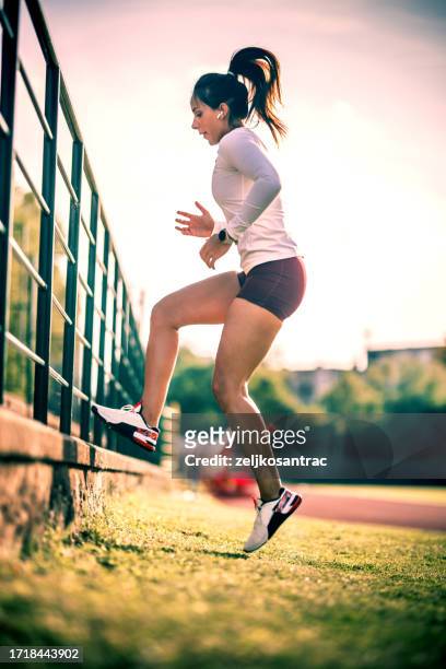 young woman exercising outside - running shorts stock pictures, royalty-free photos & images