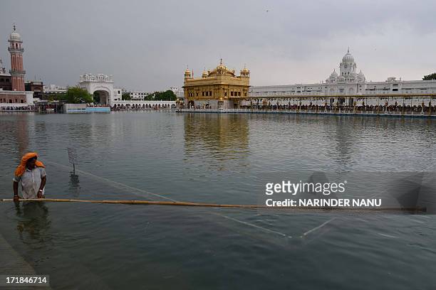 Indian Sikh devotee cleans the holy sarovar at the Sikh Shrine, The Golden Temple in Amritsar on June 29,2013. On the occasion of the 174th death...