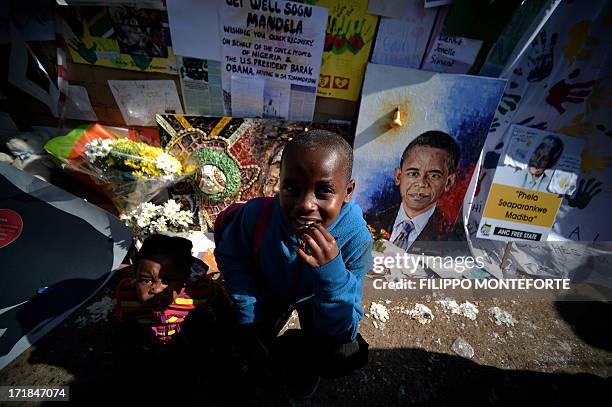 Children sit by a wall of messages and flowers left for former South African President Nelson Mandela outside the MediClinic Heart hospital in...