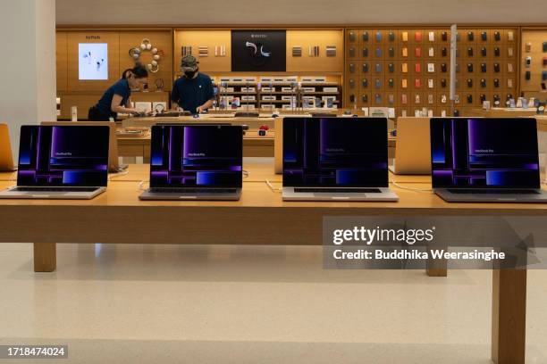 Staff stand over Apple's new MacBook laptops at an Apple store on October 05, 2023 in Kyoto, Japan.