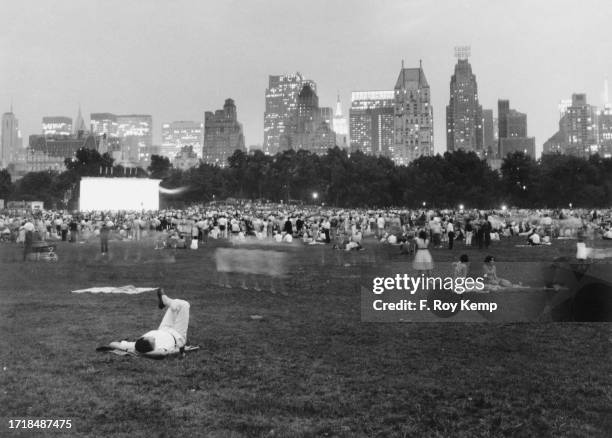 New Yorkers sitting on the grass as the New York Philharmonic Orchestra play an open-air concert at Sheep Meadow in Central Park, Upper Manhattan,...