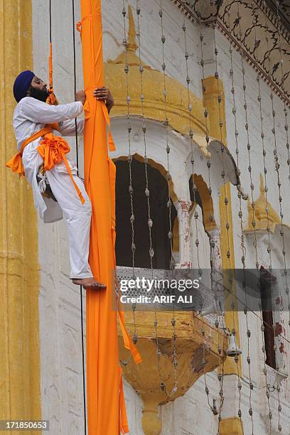 Devotee secures a cloth over a pole at a Sikh shrine in Lahore on June 29 on the 174th death anniversary of Maharaja Ranjit Singh. Singh was also...