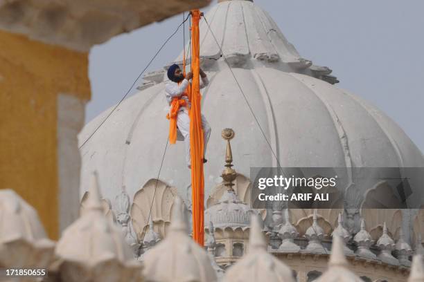 Devotee secures a cloth over a pole at a Sikh shrine in Lahore on June 29 on the 174th death anniversary of Maharaja Ranjit Singh. Singh was also...