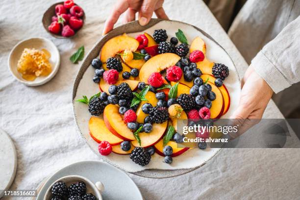 close-up of a woman serving healthy breakfast on table - fruit bowl stock pictures, royalty-free photos & images