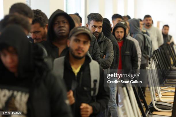 Men, many of them from Syria, queue for lunch at the initial reception facility for migrants and refugees on October 05, 2023 in Eisenhuettenstadt,...