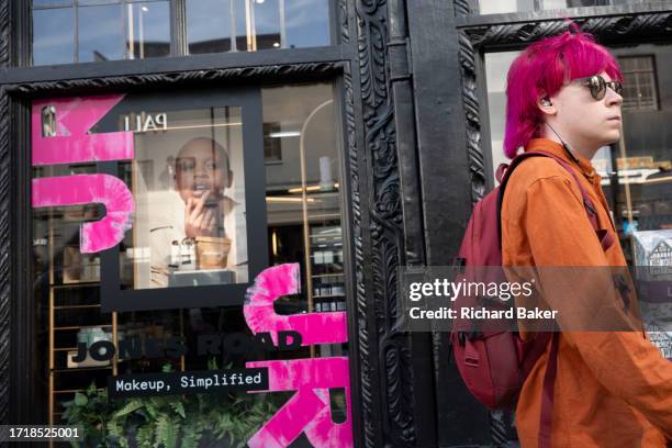 Young person with pink hair passes a window of the retailer Liberty on Great Marlborough Street, on 10th October 2023, in London, England.