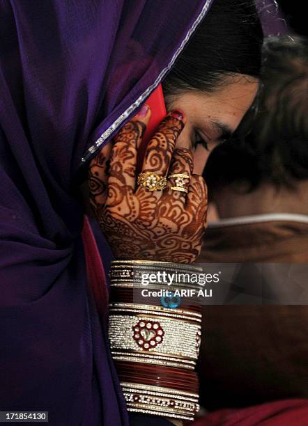 Devotee, her hand adorned with henna art, talks over her mobile phone at a Sikh shrine in Lahore on June 29 on the 174th death anniversary of...