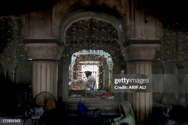 Priest reads the Sikh holy book, the Guru Granth Sahib, while pilgrims gather at a shrine in Lahore on June 29 on the 174th death anniversary of...
