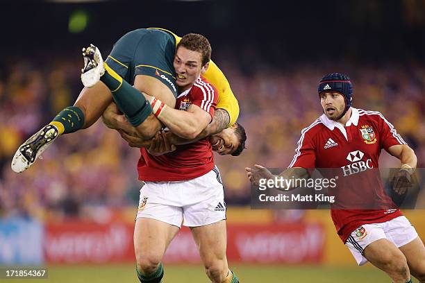 George North of the Lions lifts Israel Folau of Wallabies while carrying the ball as Leigh Halfpenny supports during game two of the International...