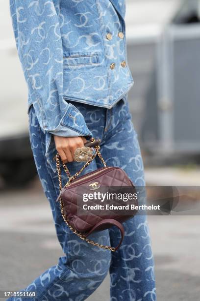 Niki Wu Jie wears a blue denim jacket with printed monograms / logos of Chanel, matching flared pants, a purple leather quilted Chanel bag, outside...